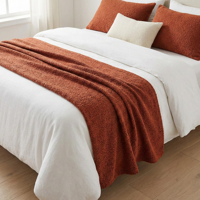 Terracotta woven bed runner on a white bed