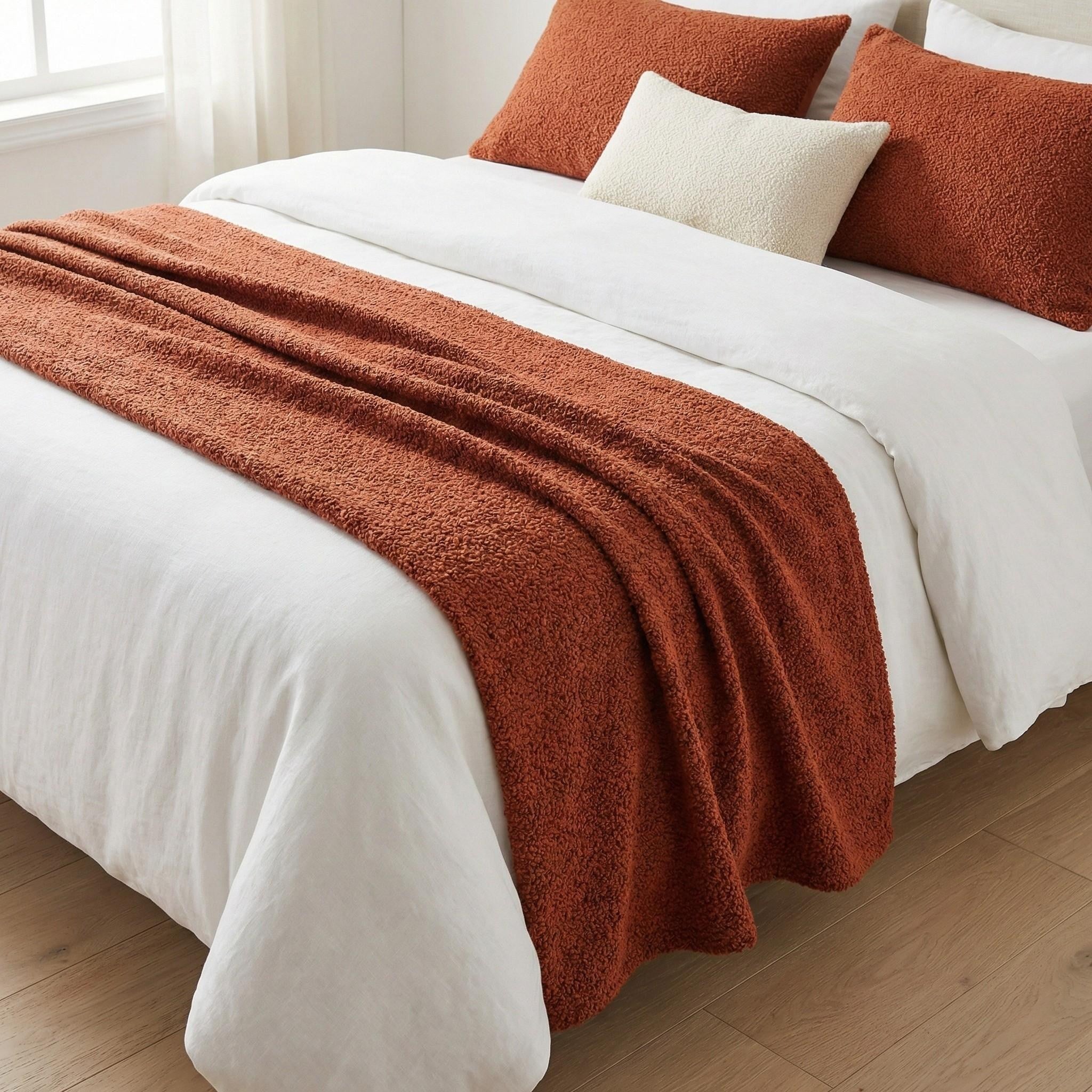 Terracotta woven bed runner on a white bed