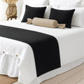 Black woven bed runner on a white bed