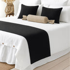 Black woven bed runner on a white bed