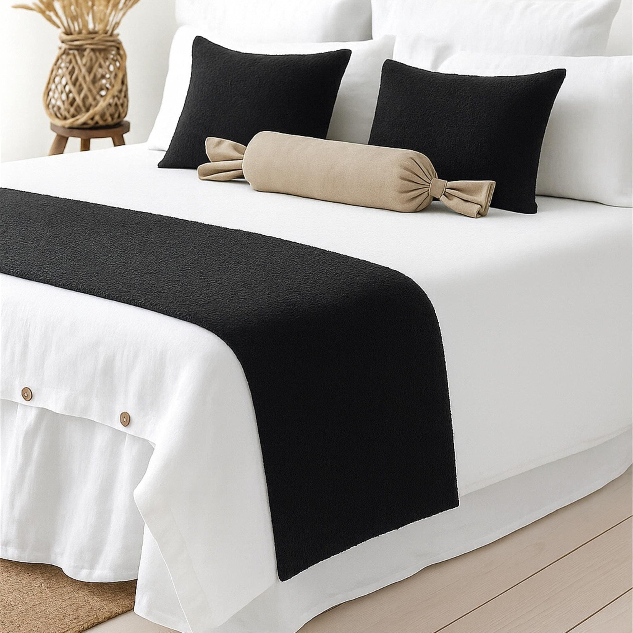 Black woven bed runner on a white bed