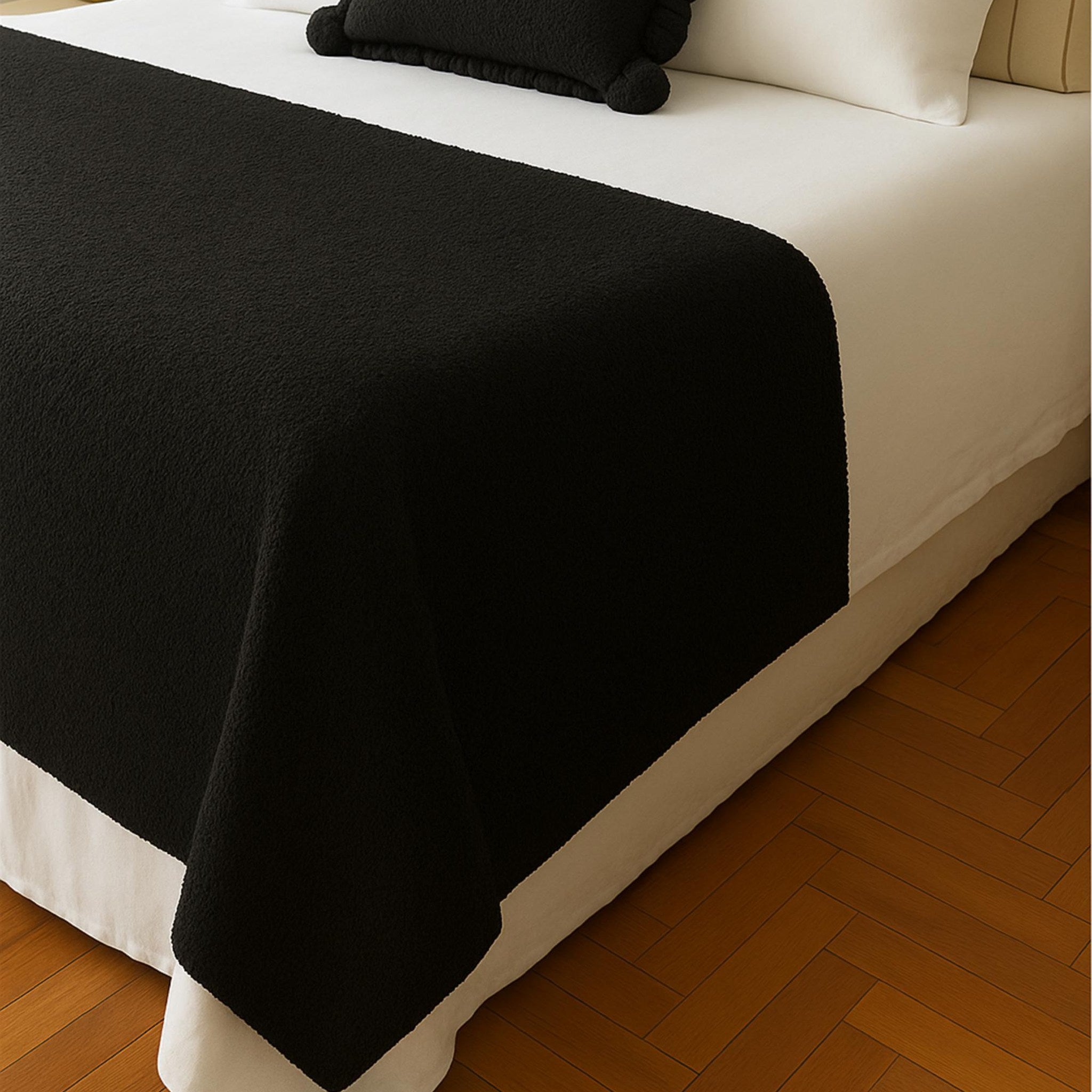 Black woven runner across foot of bed