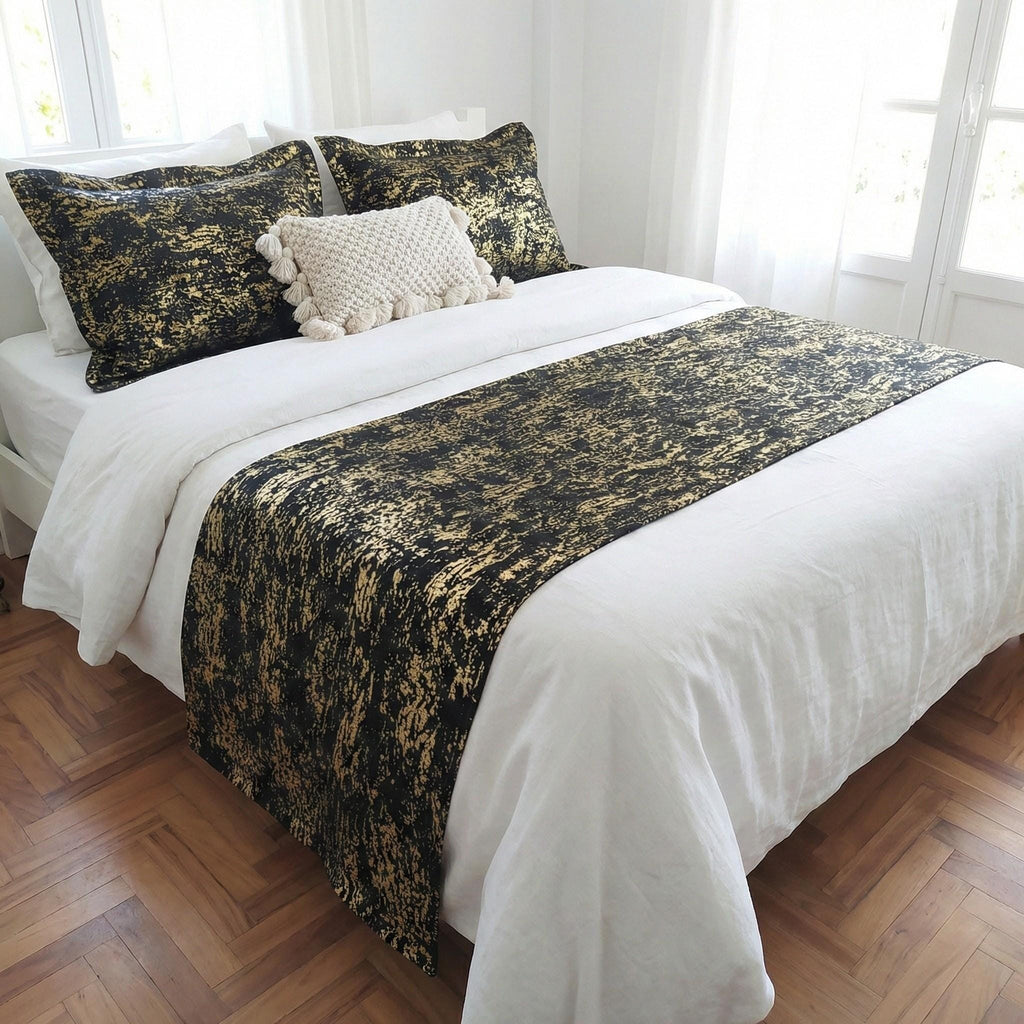 Black and gold velvet bed runner on a white bed