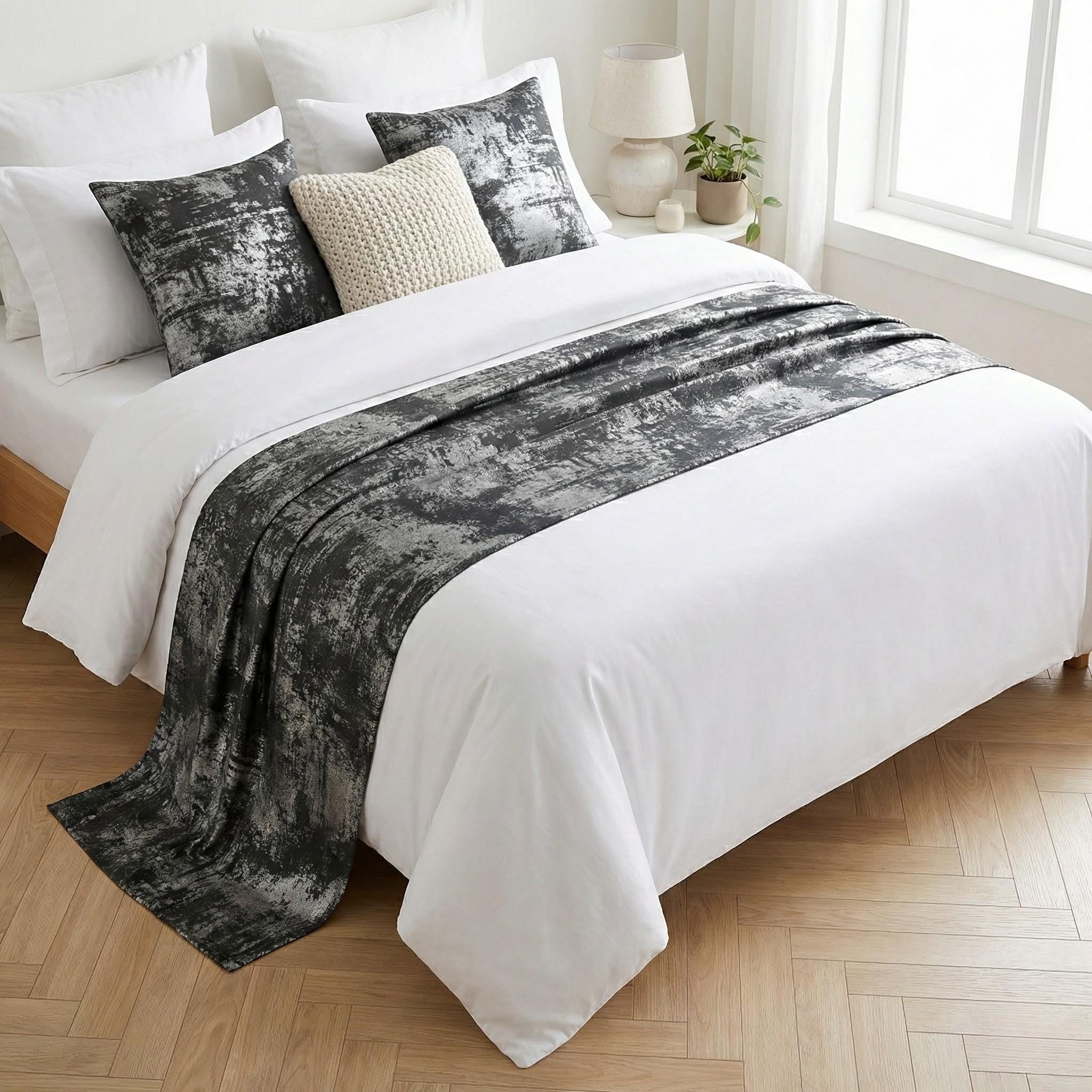 Gray and silver velvet bed runner on a white bed
