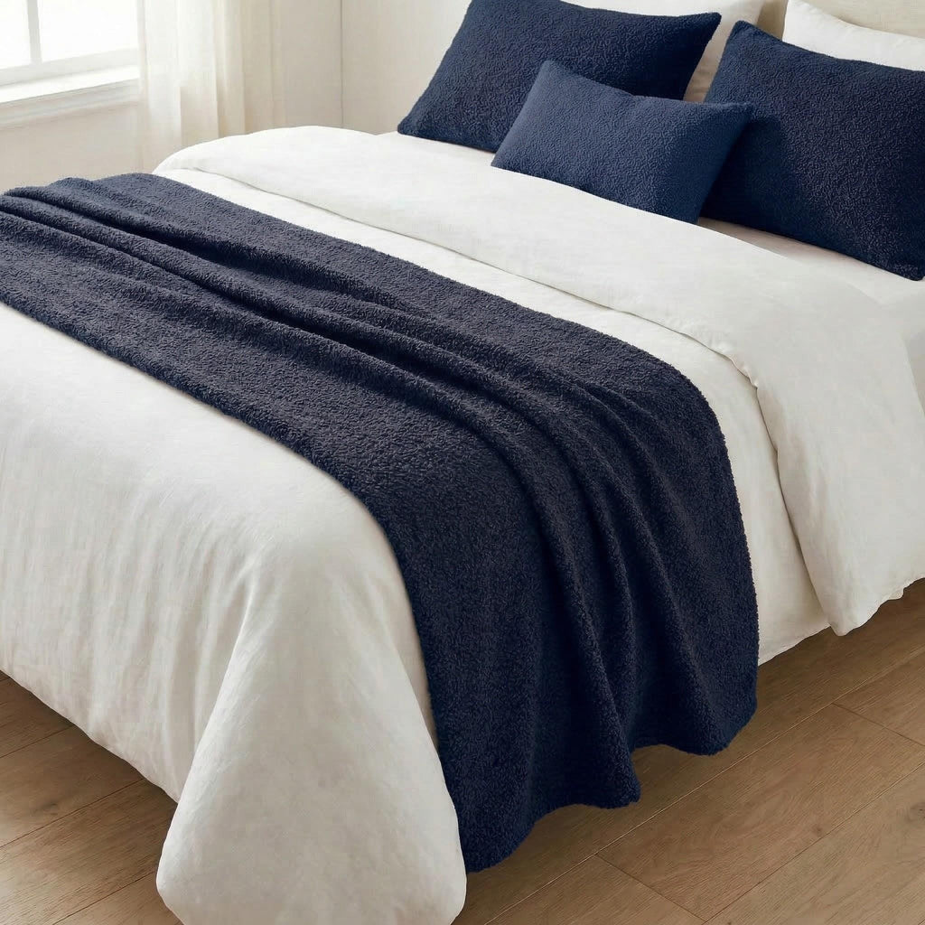 Navy blue woven bed runner on a white bed