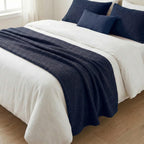 Navy blue woven bed runner on a white bed