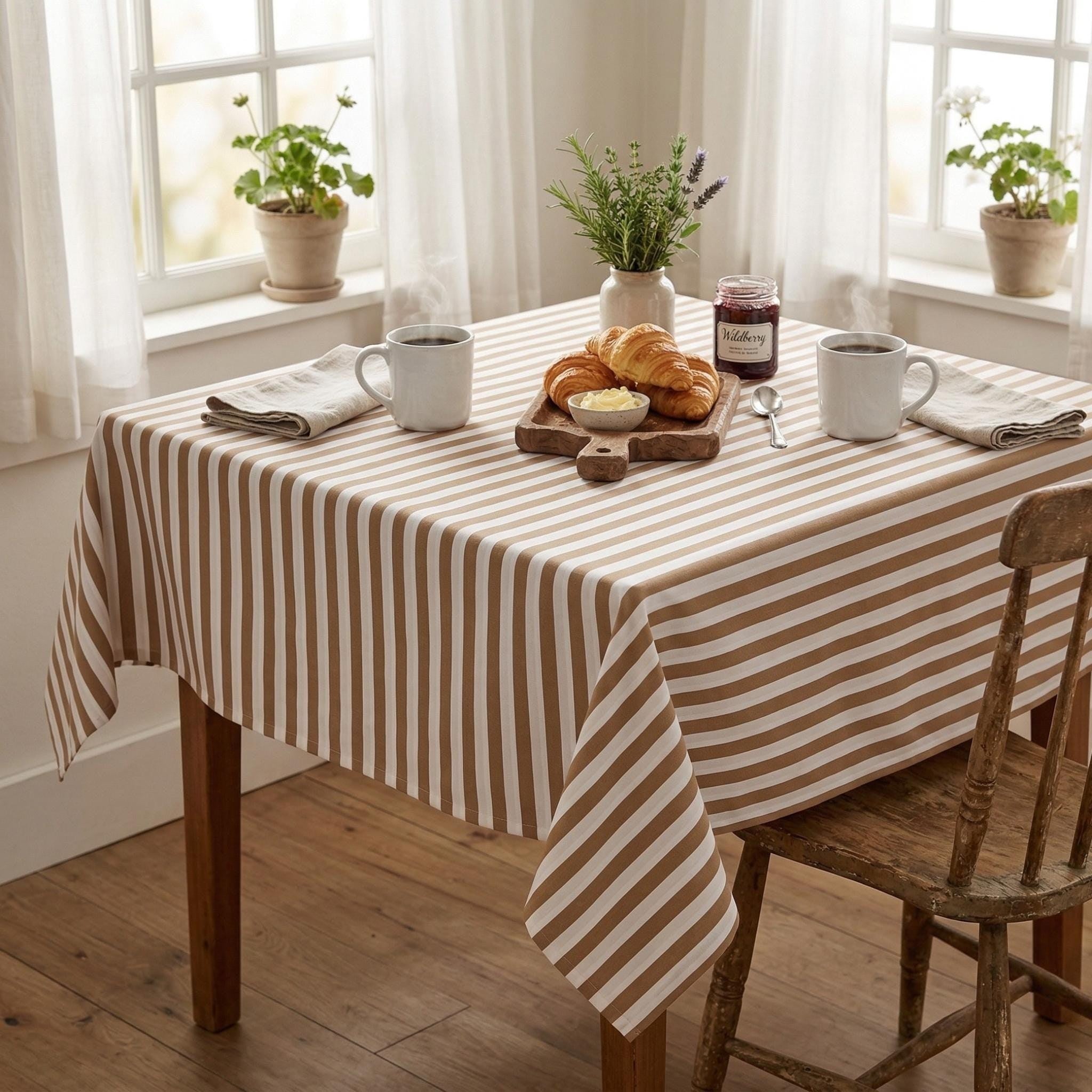 Dark beige striped cotton tablecloth on a rustic wooden dining table