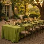 Long dinner party table with green tablecloth in garden